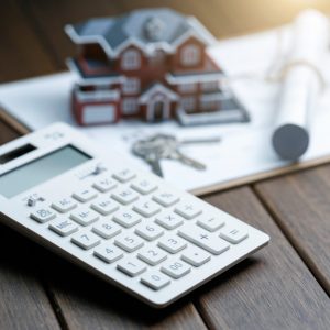 a calculator in front of a Villa house model with a blueprint